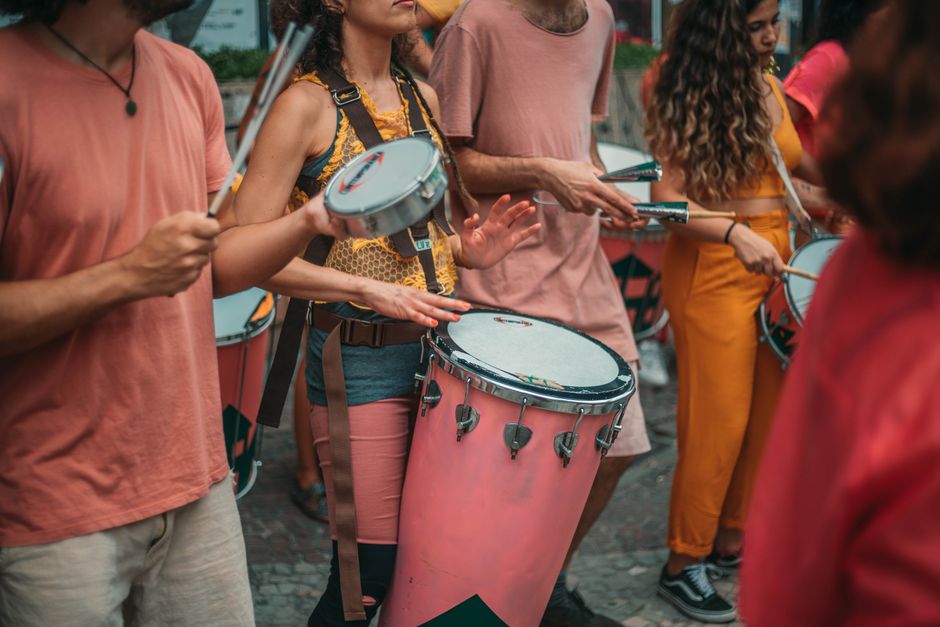 Turismo Sustentável — Vibrant street parade with musicians playing various drums and percussion instruments.