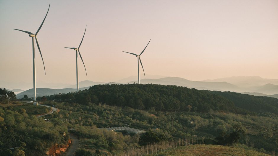 Turismo Sustentável — Wind turbines on a hilly rural landscape during dusk, promoting green energy.