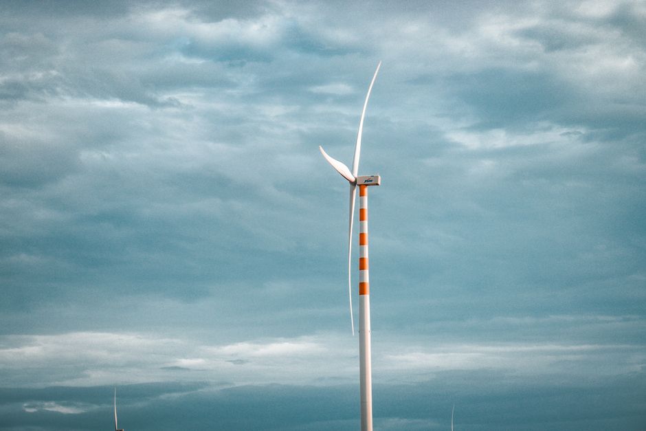Turismo Sustentável — A single wind turbine stands tall against a backdrop of cloudy skies, symbolizing renewable energy.